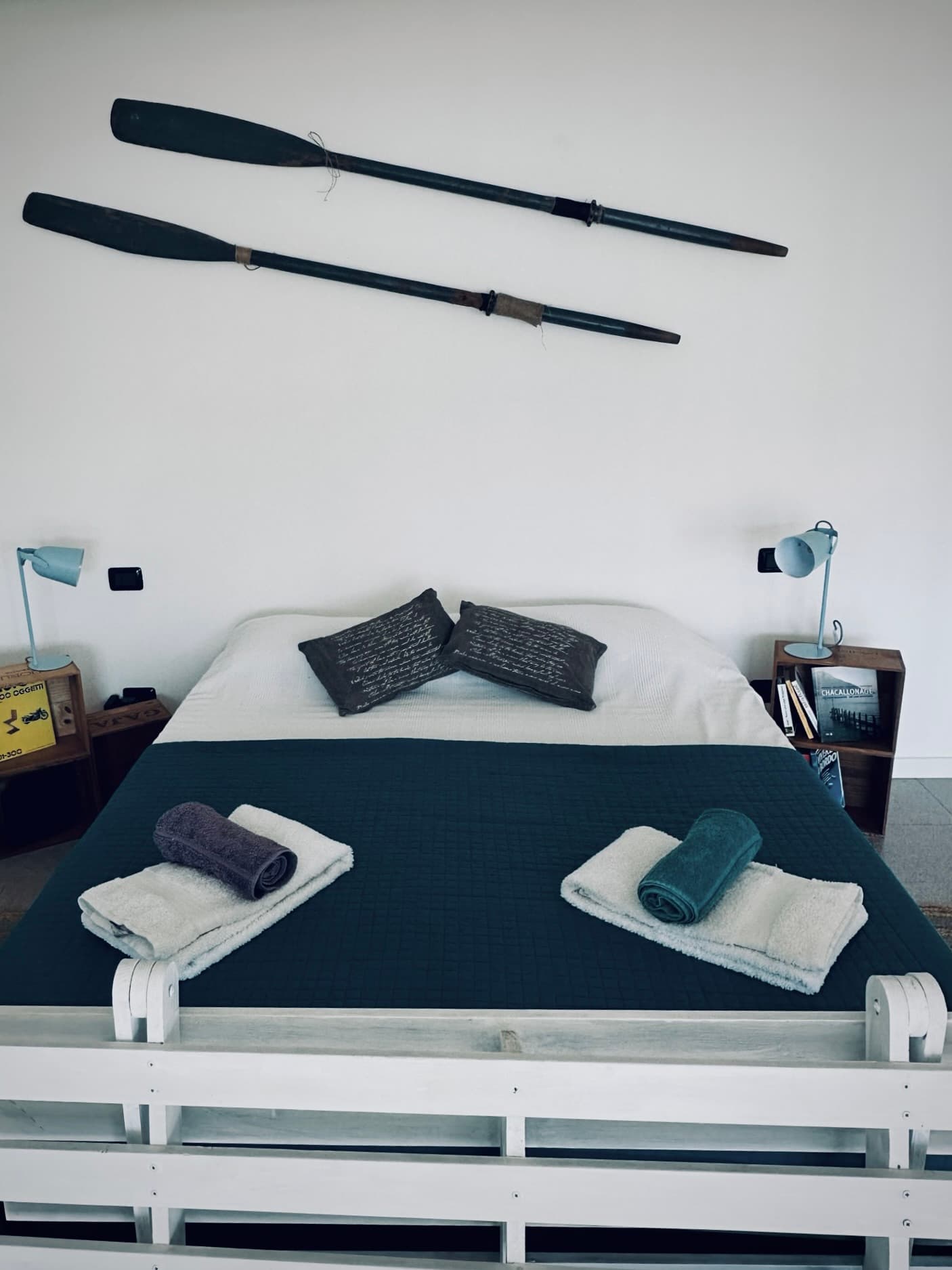 The prepared bed with folded towels and wooden oars above