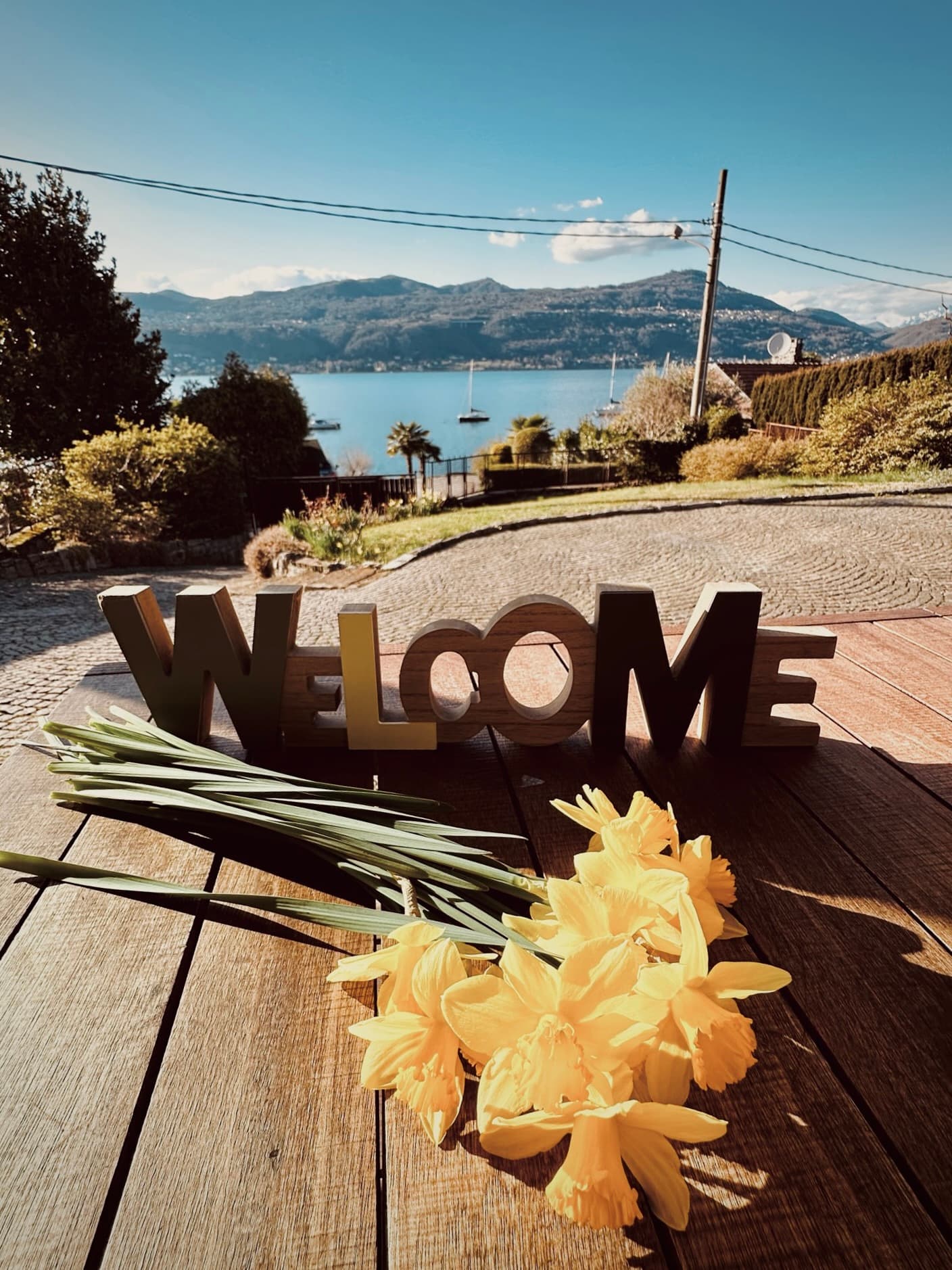 A wooden welcome sign and daffodils overlooking the lake