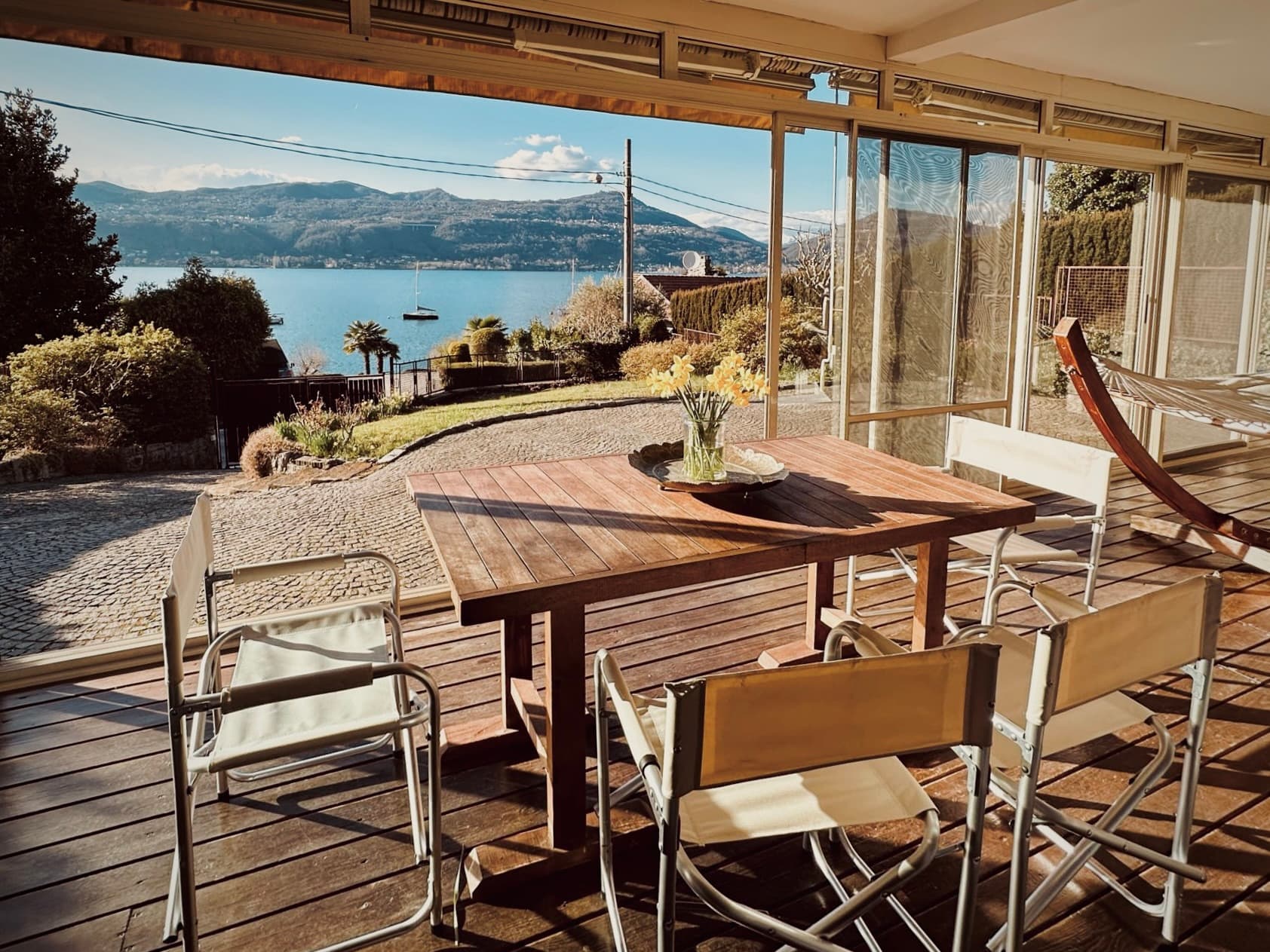 The dining table beneath the covered veranda with the lake beyond