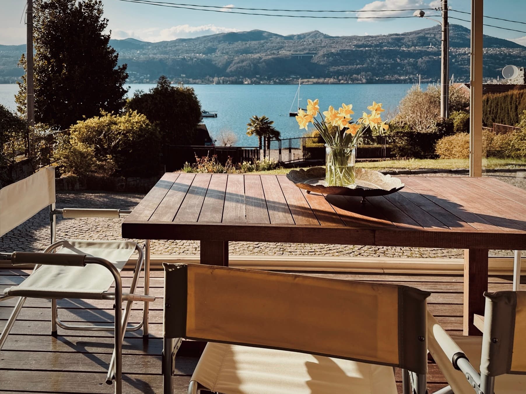 A flower-filled vase on the veranda table with the lake beyond