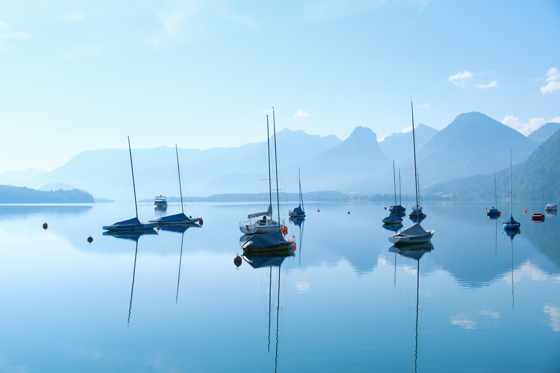 Sailboats resting on calm open water beneath the mountains